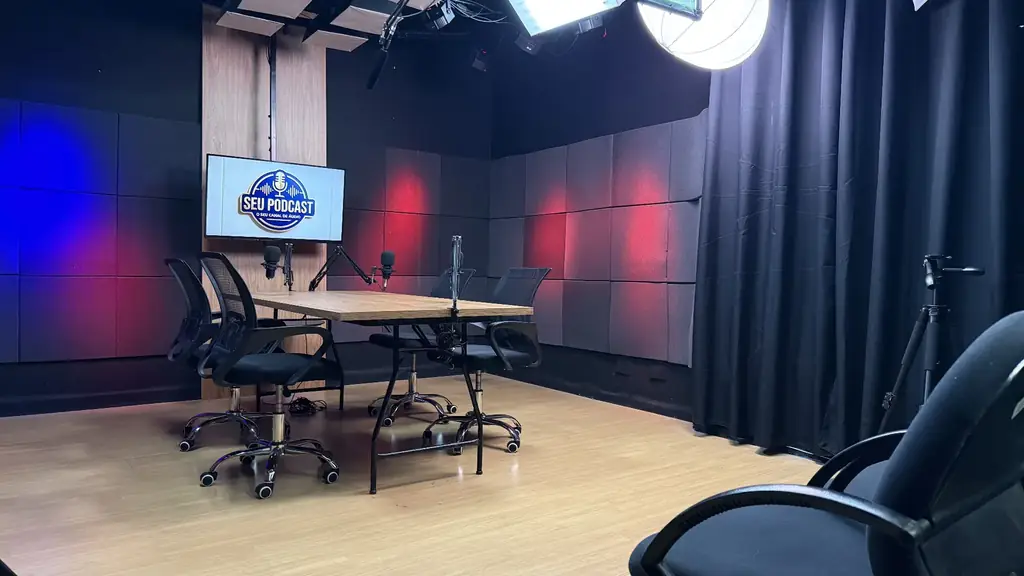 Visão ampla do estúdio de podcast OFBOX com mesa central, cortinas acústicas e área livre para captação.